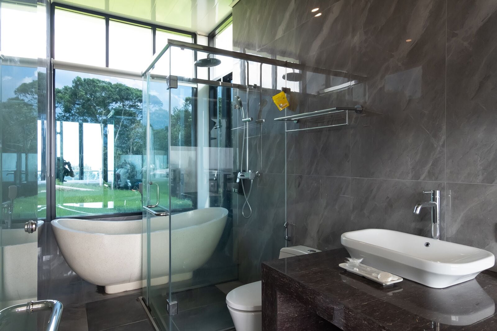 Un baño moderno con una bañera independiente, ducha con mampara de vidrio y tocador con lavamanos.