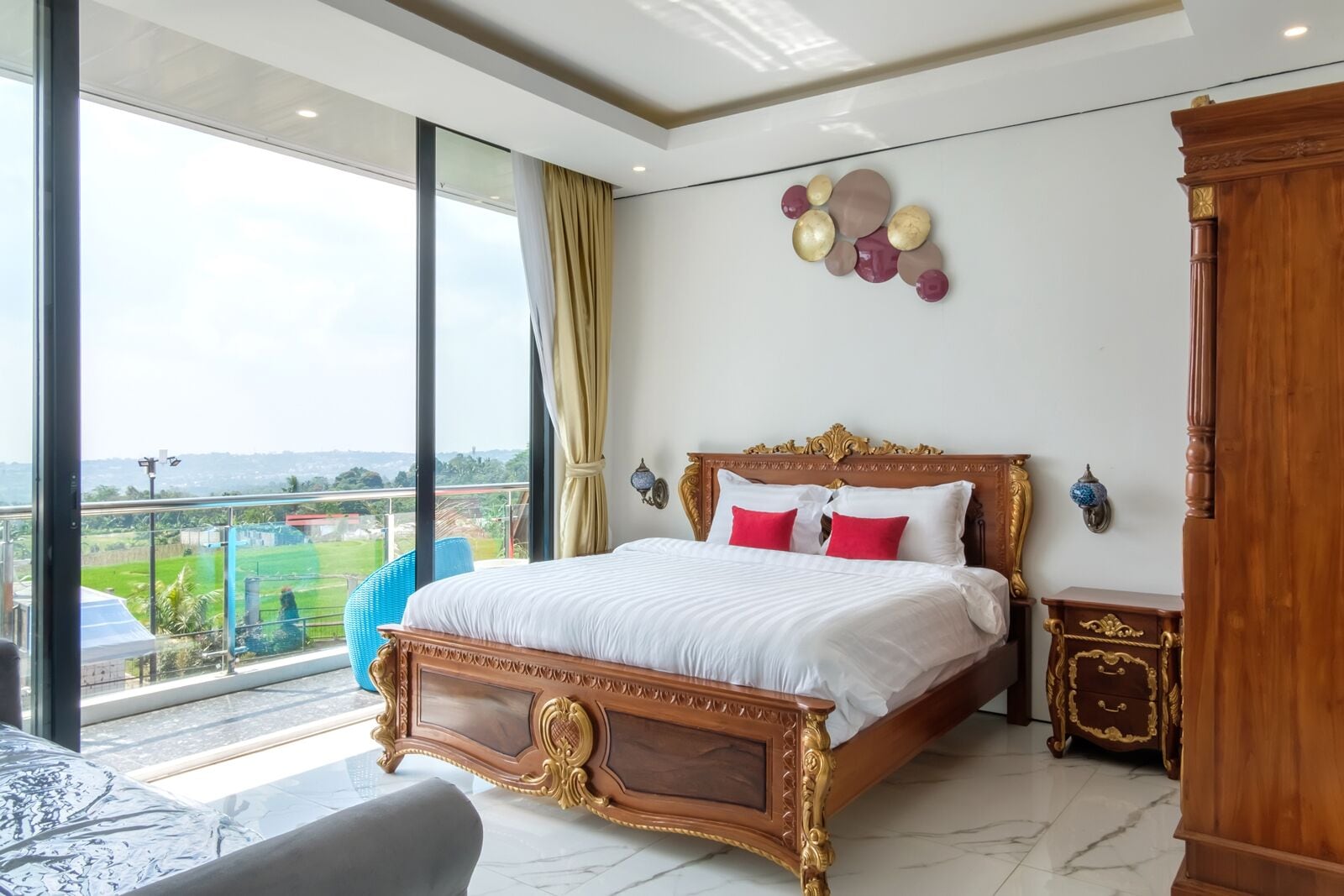 A spacious bedroom with a large bed, a view of a green landscape, and a balcony.