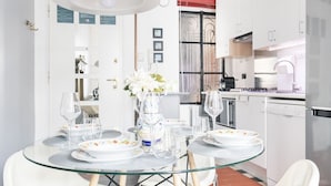 Een moderne keuken met witte kasten, een glazen eettafel en een vaas met bloemen.