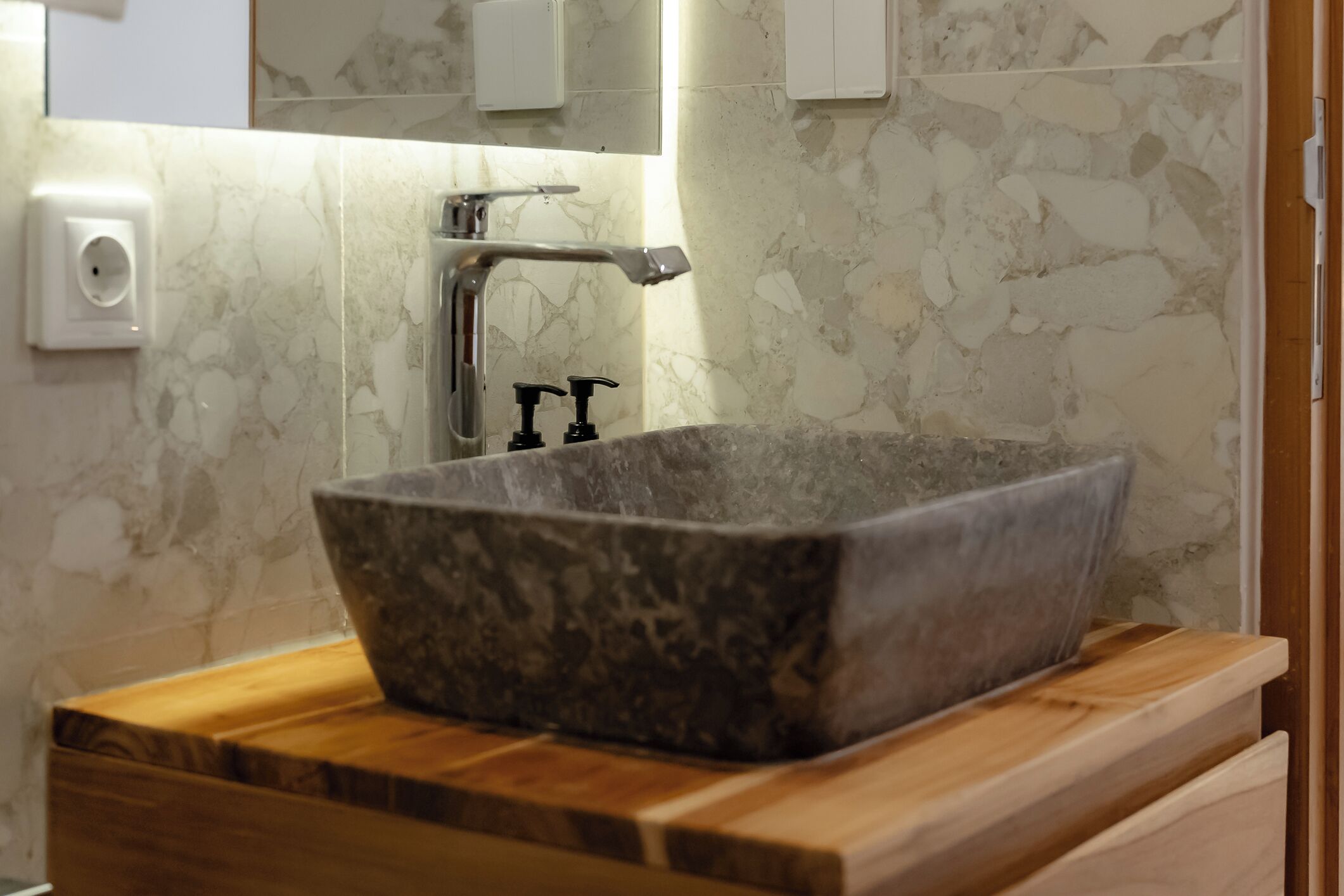 A bathroom with a stone sink, wooden countertop, and a mirror above the sink.