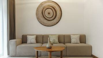 A living room with a beige sofa, a round coffee table, and a decorative wall piece.