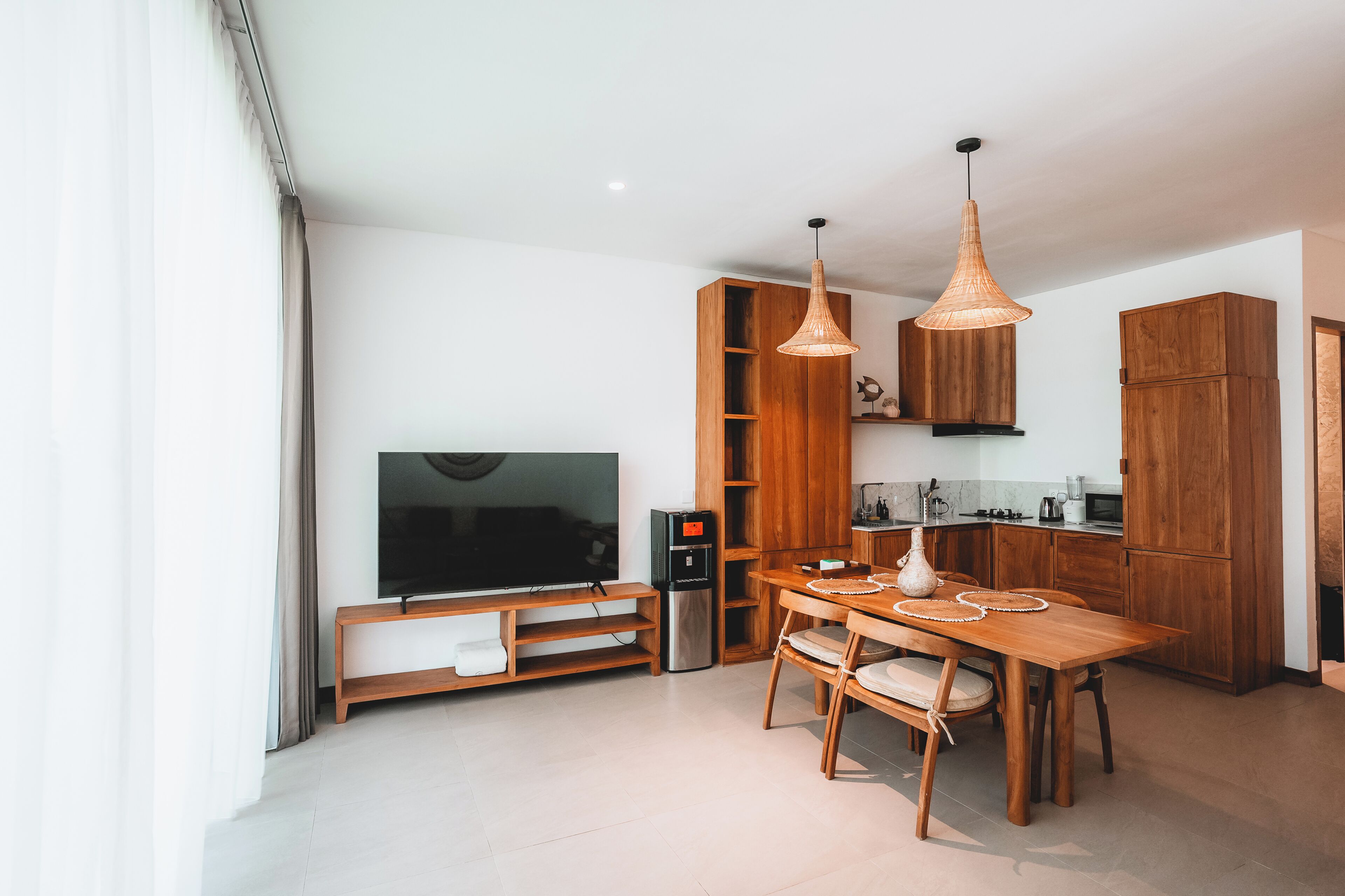 A modern kitchen with wooden cabinets, a built-in TV, and a dining area with a wooden table and chairs.