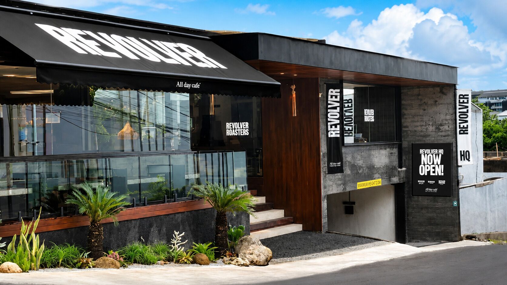 Un edificio moderno con un'insegna che riporta 'REVOLVER' e 'caffè aperto tutto il giorno'.