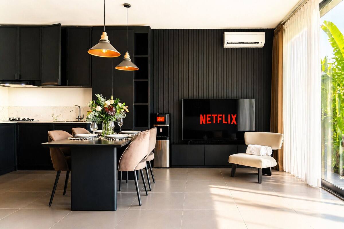 A modern kitchen with a dining area, a flat-screen TV, and a large window with a view.