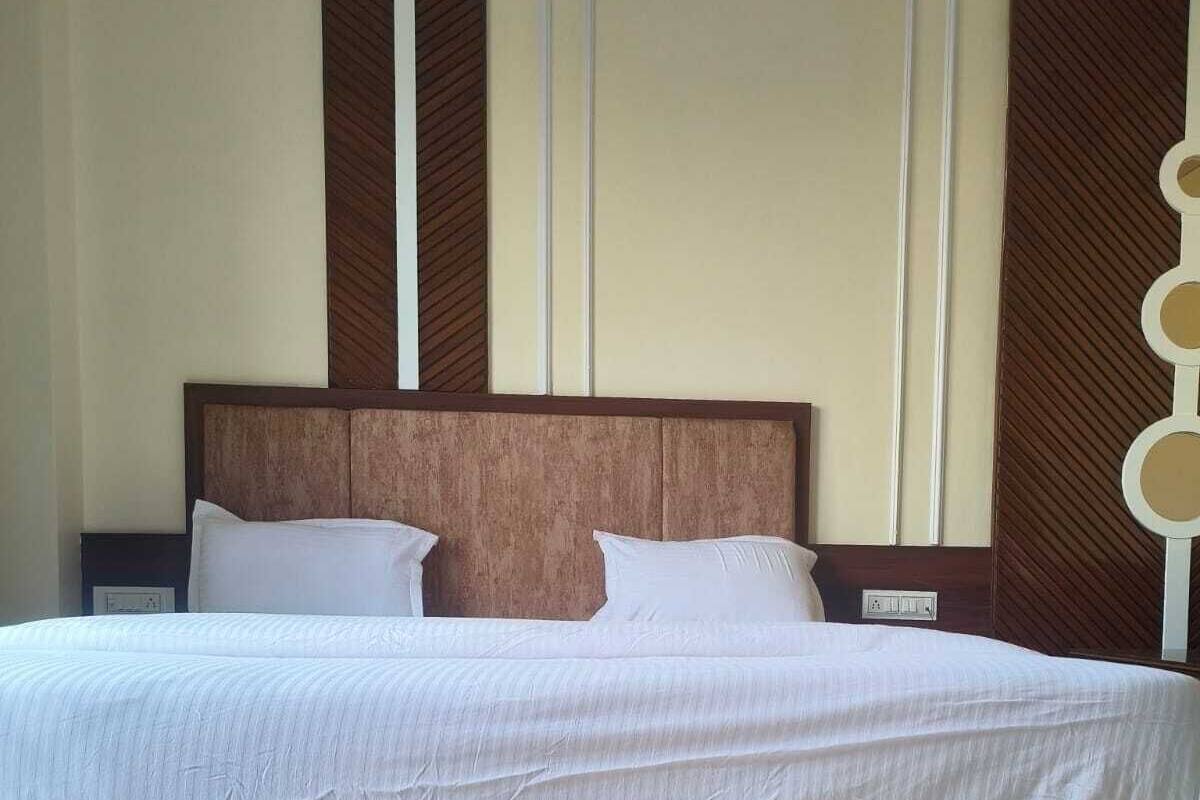 A large bed with a wooden headboard, white bedding, and a simple nightstand.