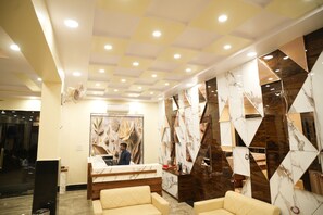 Een hotel receptie met een modern design, met een receptiebalie, een zithoek en decoratieve wandpanelen.
