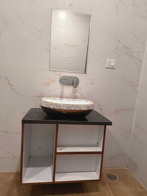 A bathroom with a marble sink, a mirror, and a shelf unit. - Hotel Kamla Heritage - Shivpuri (Shivpuri)