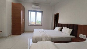 A hotel room with two beds, a window, an air conditioning unit, and a wooden wardrobe.