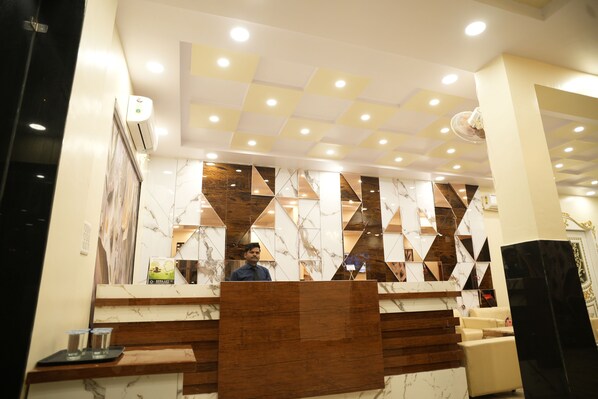 A hotel reception area with a marble counter, a wooden reception desk, and a ceiling with recessed lighting. - Hotel Kamla Heritage - Shivpuri (Shivpuri)