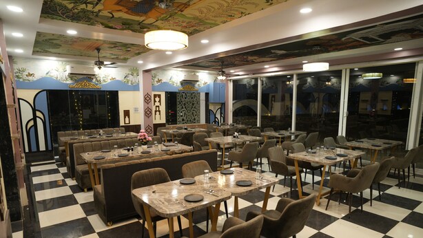 A restaurant with checkered flooring, multiple dining tables and booths, and a ceiling with a mural.