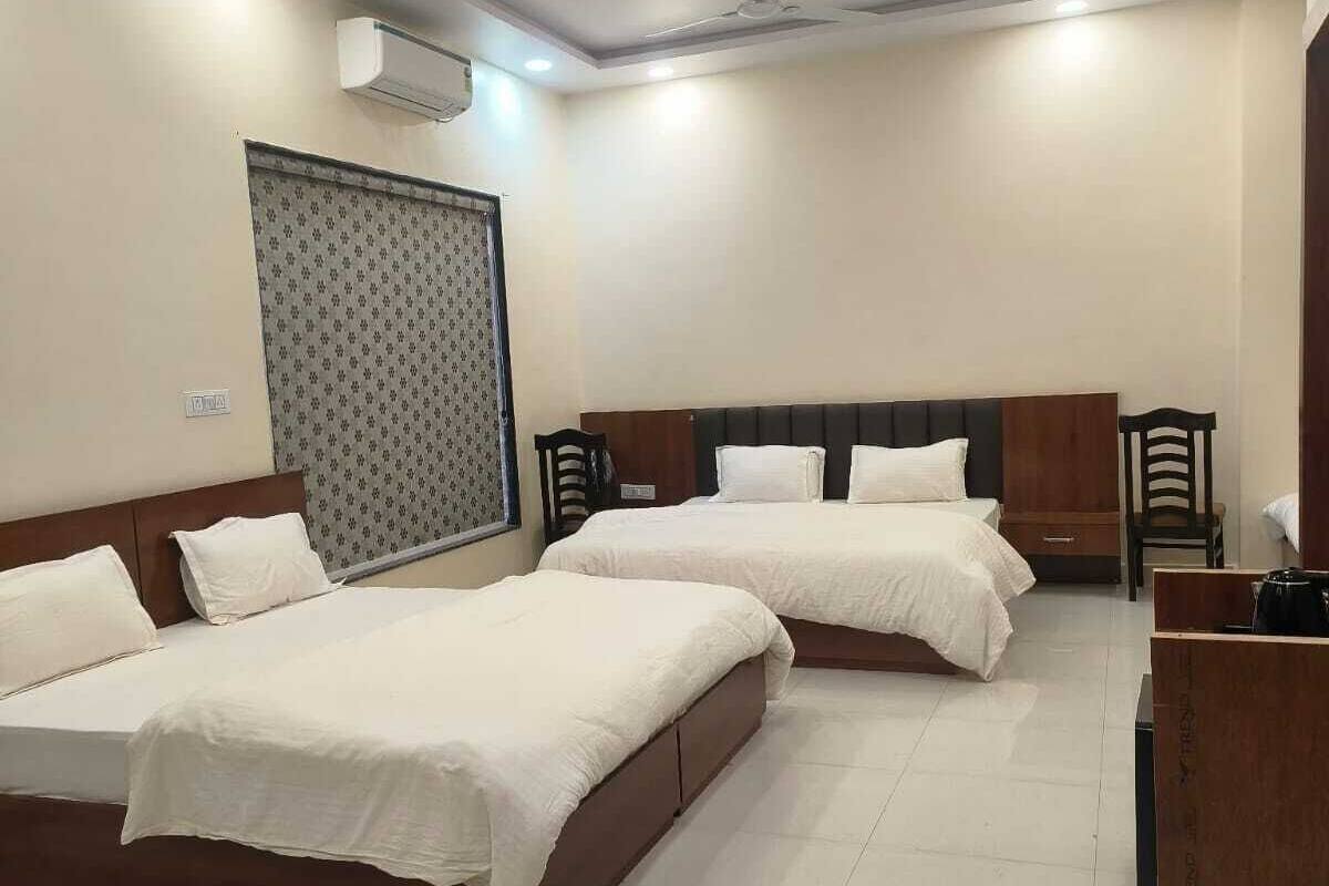 A hotel room with two beds, a wooden desk, and a wardrobe.