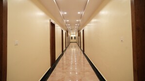 A long, narrow hallway with a shiny, reflective floor and recessed lighting on the ceiling.