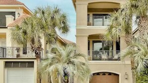 A two-story house with a balcony, a garage, and palm trees. - Destin: Private Beach, Pool, 4 En-Suites (Destin)