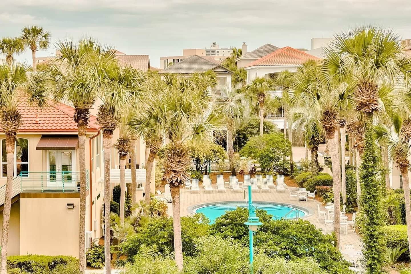 A resort with a pool surrounded by palm trees and lounge chairs.