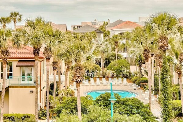A resort with a pool surrounded by palm trees and lounge chairs.