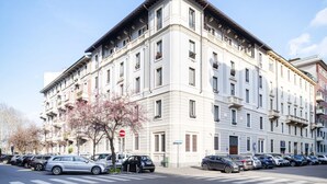 Un edificio de varios pisos con un estilo arquitectónico clásico, que presenta una fachada simétrica, múltiples ventanas y balcones.