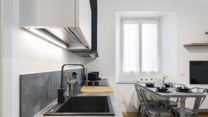 Una cocina moderna con un lavamanos integrado, electrodomésticos de acero inoxidable y un comedor con una mesa grande y sillas.