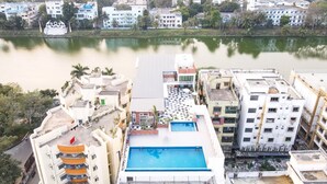 A high-rise building with a rooftop pool, surrounded by other buildings and a body of water. - HOTEL LAKE VIEW (Baharampur)