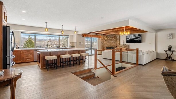 A modern kitchen with a central island, bar stools, and a dining area. - Estate on Bow River 25 Min to  DT YYC 5BR w AC (Calgary)