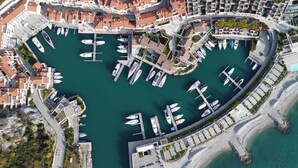 Vue aérienne d’un port de plaisance où sont amarrés des bateaux, entouré de bâtiments aux toits recouverts de tuiles rouges.