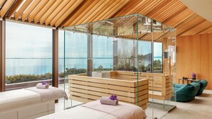 Une salle de spa avec un plafond en bois, des cloisons en verre et une vue sur la mer.