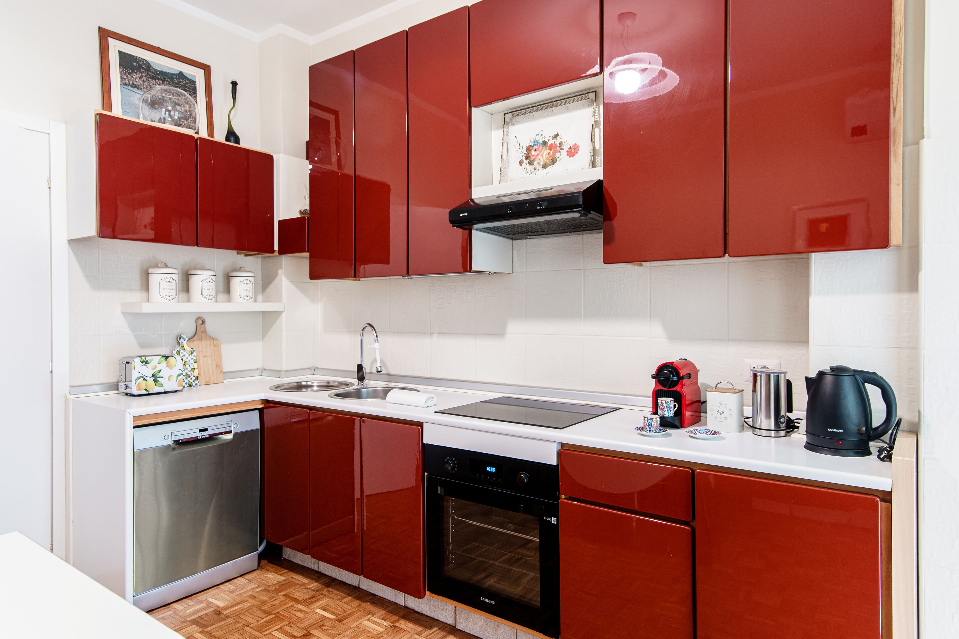 A modern kitchen with red cabinets, stainless steel appliances, and a white countertop.