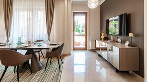 A modern dining area with a table set for four, a sofa, and a TV mounted on the wall. - Cernobbio Garden View (Cernobbio)