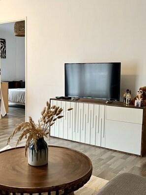 Relax in this stylish living room with a flat-screen TV, wooden coffee table, and natural decor.