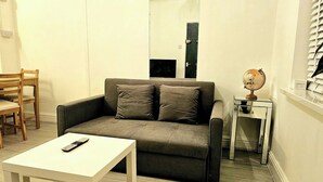 Una sala de estar con un sofá, una mesita, una silla, un globo terráqueo sobre una mesita auxiliar y una ventana con persianas.