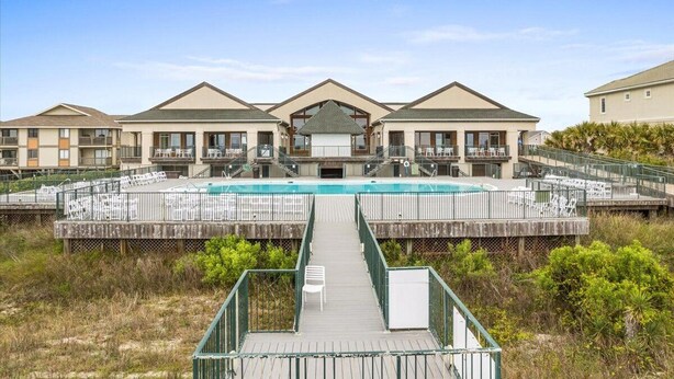 A resort with a central pool, multiple balconies, and a wooden walkway leading to the pool. - NEW LISTING-UPDATES!-4br 4ba-DOG FRIENDLY-towels,linens,pool club.<br>Golf cart friendly (Ocean Isle Beach)