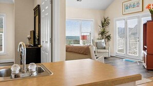 A kitchen with a large island, a dining area with a chair and table, and a living room with a ceiling fan and a plant. - NEW LISTING-UPDATES!-4br 4ba-DOG FRIENDLY-towels,linens,pool club.<br>Golf cart friendly (Ocean Isle Beach)
