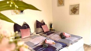 A neatly made bed with multiple pillows and a rolled-up towel, a bedside table with a plant, and framed artwork on the wall. - Zuhause im Ruhrgebiet 2 mit Balkon (Oberhausen)