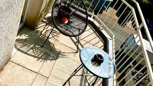 A patio area with two metal chairs and a small table, surrounded by a white metal railing. - Zuhause im Ruhrgebiet 2 mit Balkon (Oberhausen)