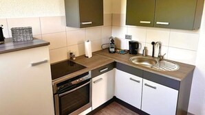 A compact kitchen with a built-in oven, a coffee maker, and a sink. - Zuhause im Ruhrgebiet 2 mit Balkon (Oberhausen)