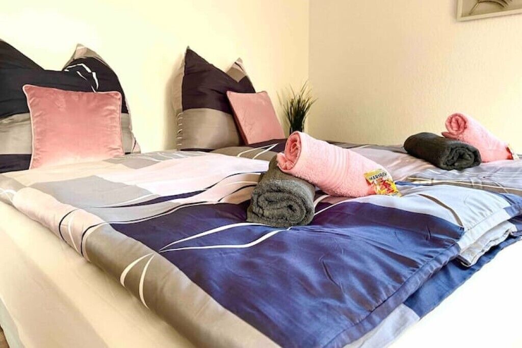 Un lit bien fait, avec des serviettes pliées et une petite plante en pot.