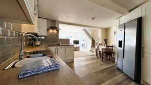 Een moderne keuken met een houten aanrecht, roestvrijstalen apparatuur en uitzicht op de woonkamer.