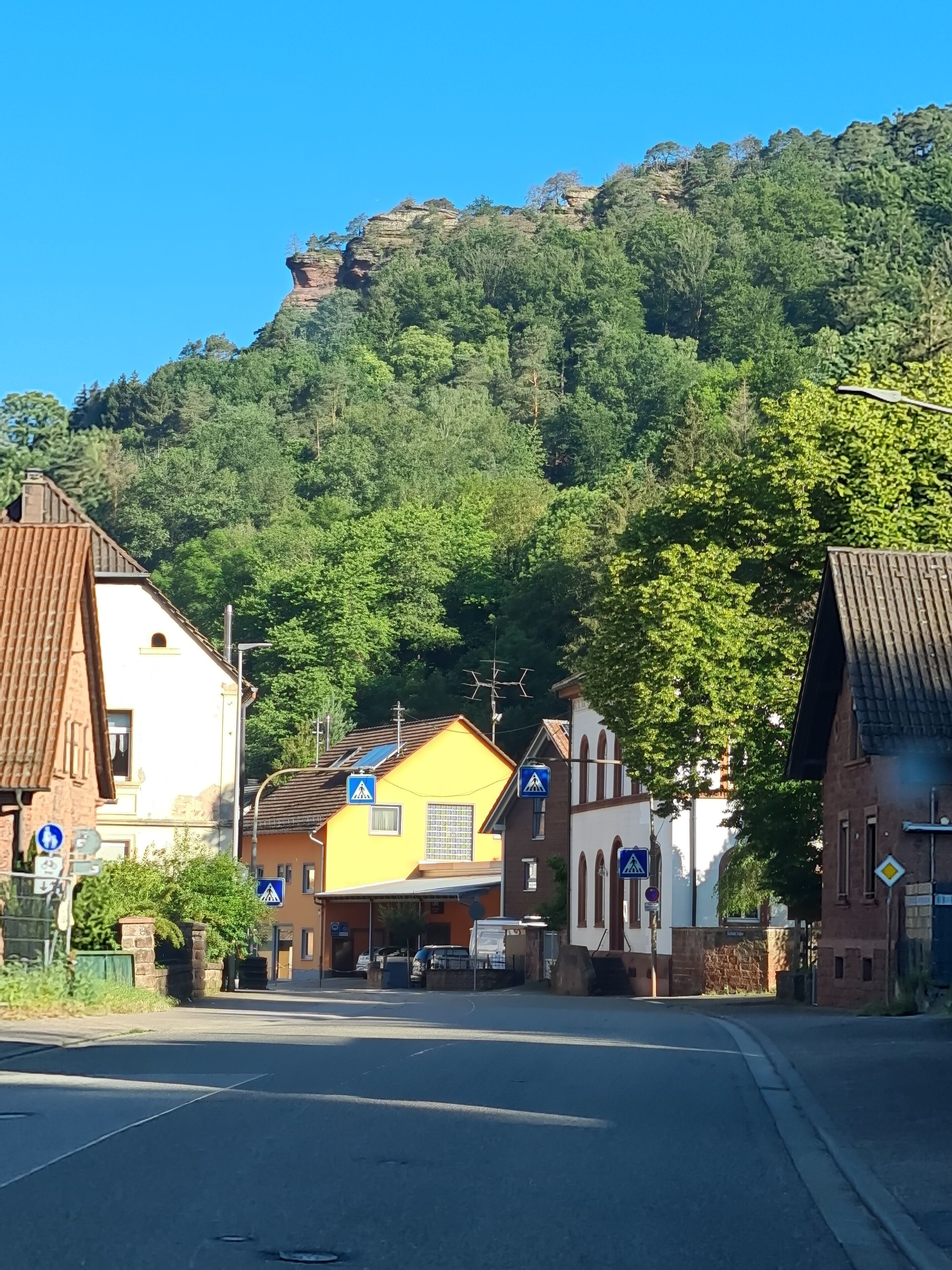A street with traditional European architecture, including a yellow building and a church with a bell tower.