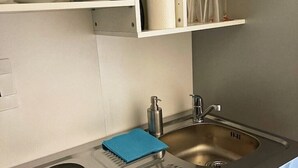 A modern kitchen with a stainless steel sink, a soap dispenser, and a blue towel on the counter. - Apartment Nähe Flughafen DUS mit Balkon (Düsseldorf)