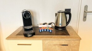 A kitchenette with a coffee maker, a kettle, and a set of colorful cups on a wooden countertop. - Apartment Nähe Flughafen DUS mit Balkon (Düsseldorf)