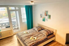 Un dormitorio con cama, radiador, ventana con cortinas y decoración en la pared.