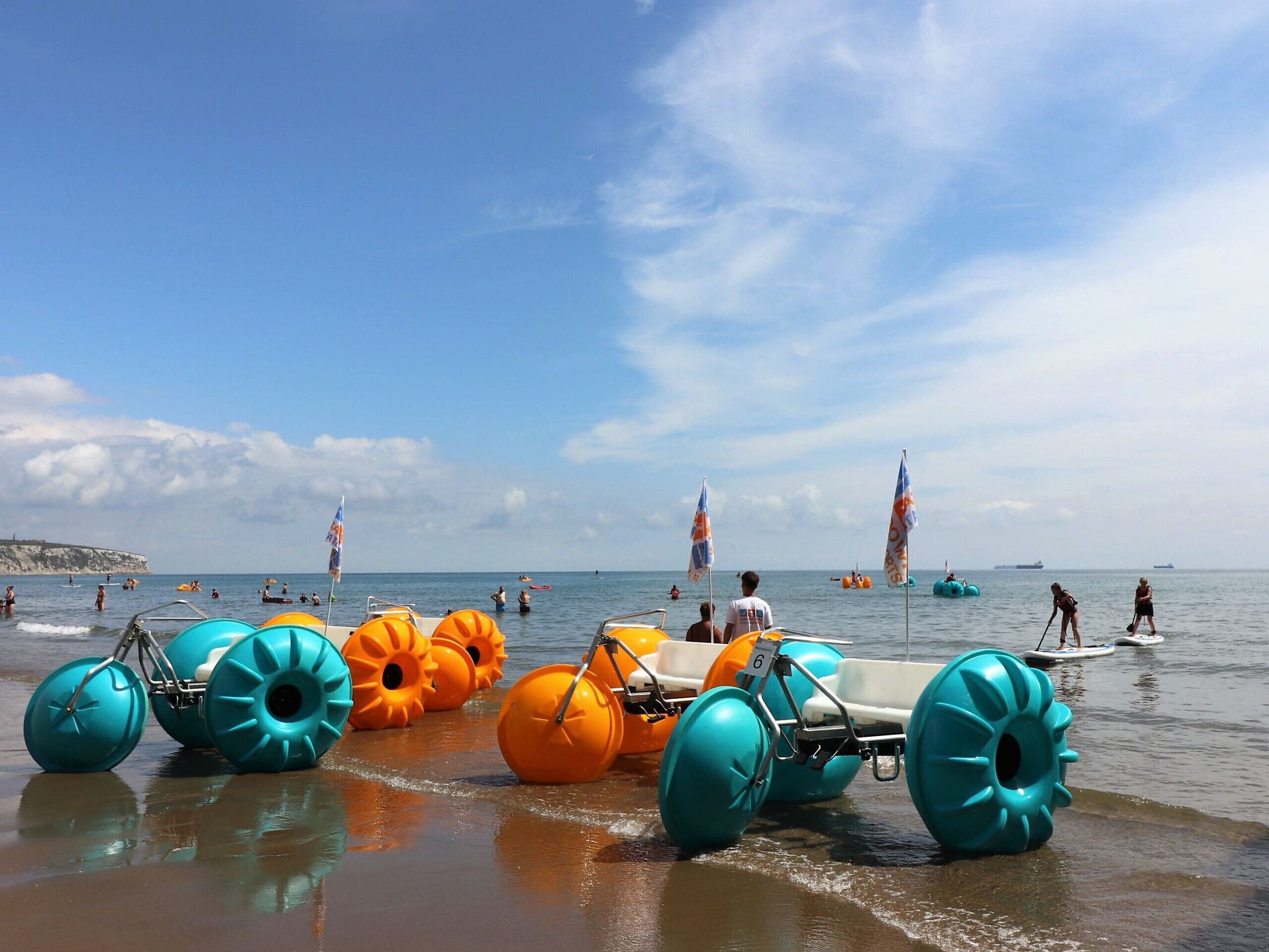 A beach with inflatable water toys and people in the water.