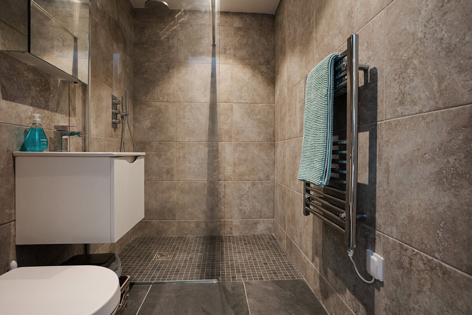 A modern bathroom with a shower, a toilet, and a sink.