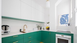 A modern kitchen with white and green cabinetry, a built-in oven, and a coffee maker. - Verdant and Vivacious, by Veeve (Paris)