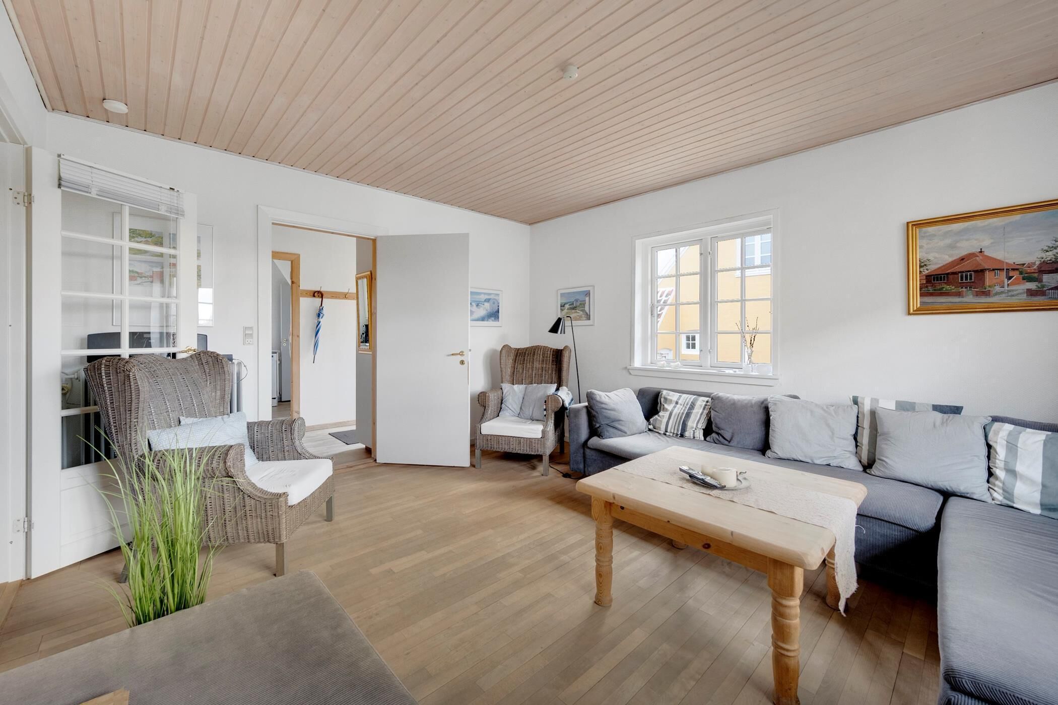 Un salon spacieux avec un plafond en bois, un ensemble de canapés, une table à manger et une chaise.
