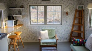 Una habitación acogedora con una silla verde, una escalera de madera y una ventana con vistas a árboles.