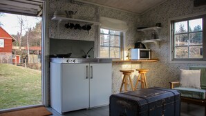 Una cocina funcional con armarios blancos, microondas y un pequeño comedor con taburetes.