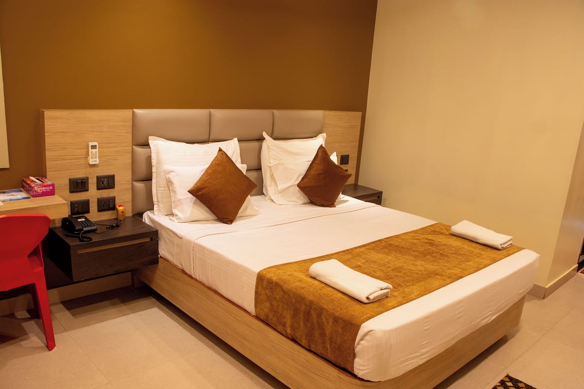 A hotel room with a bed, a desk, and a chair.