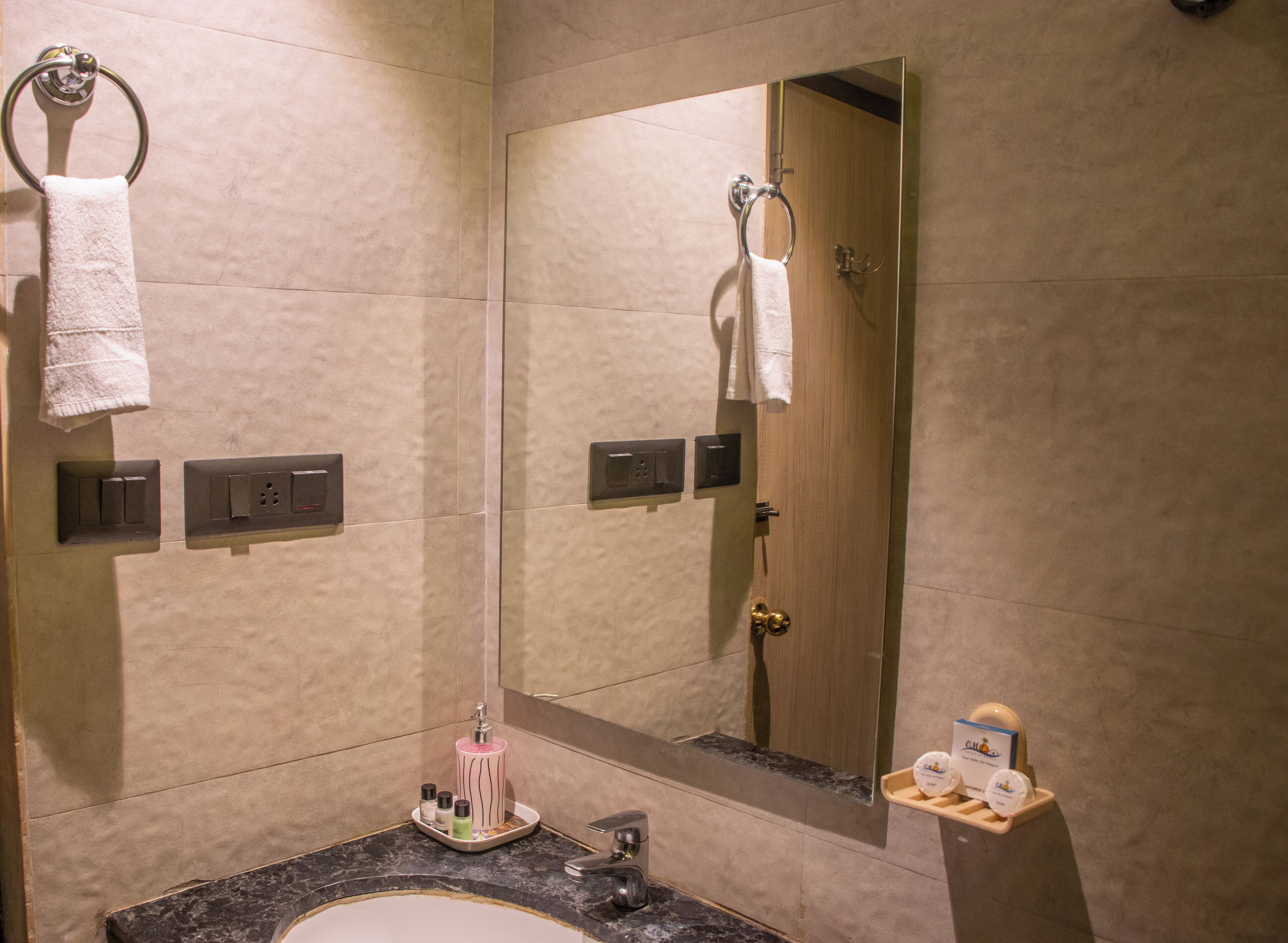 Une salle de bain moderne avec un lavabo en marbre, un grand miroir, un porte-serviettes et une porte de douche.