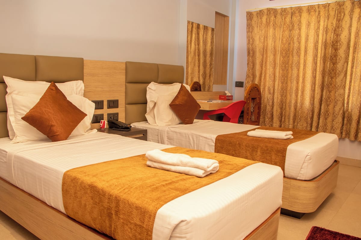 A hotel room with two beds, a desk, and a mirror.