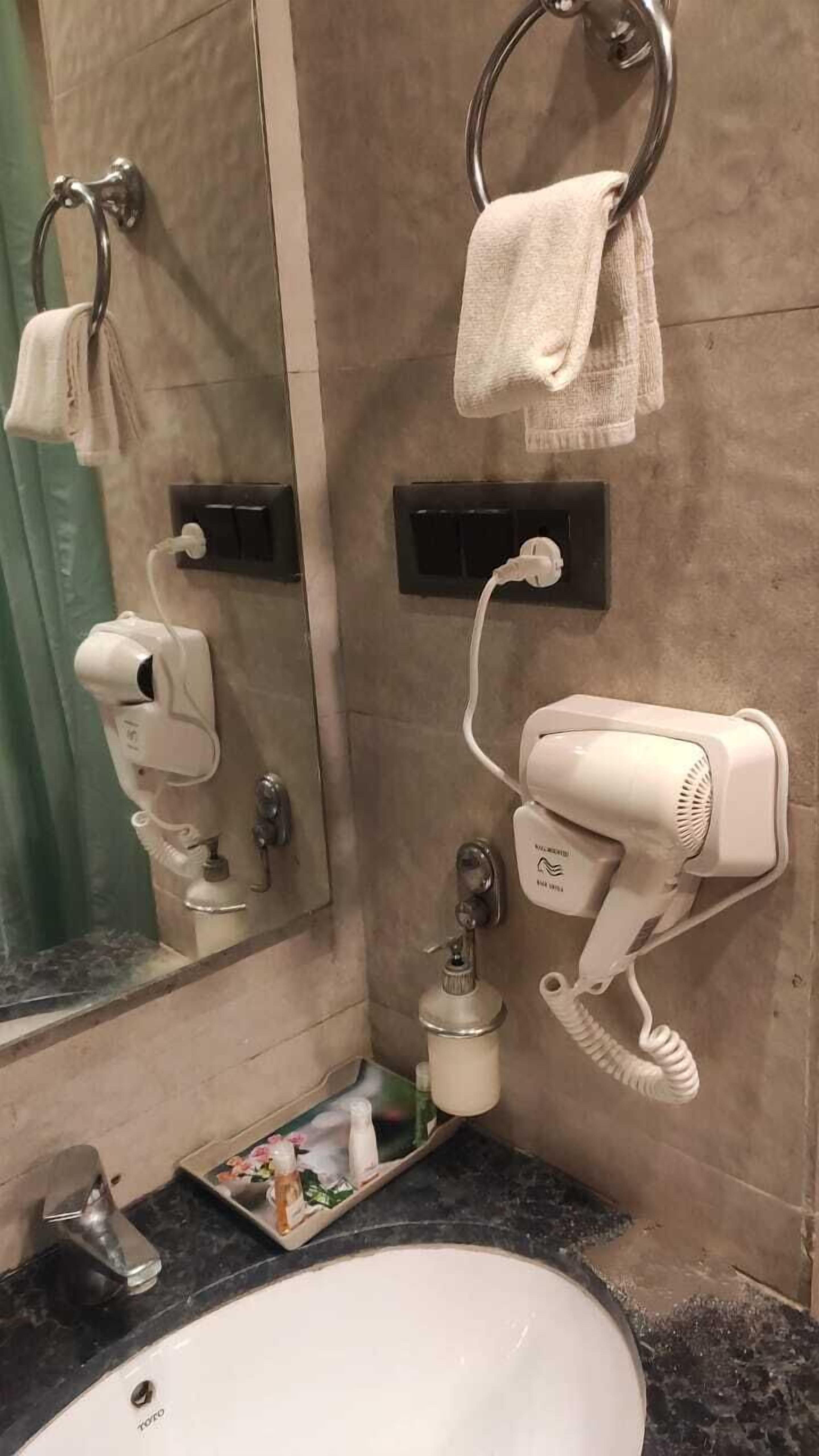 Un bany amb un lavabo, un assecador i un mirall.